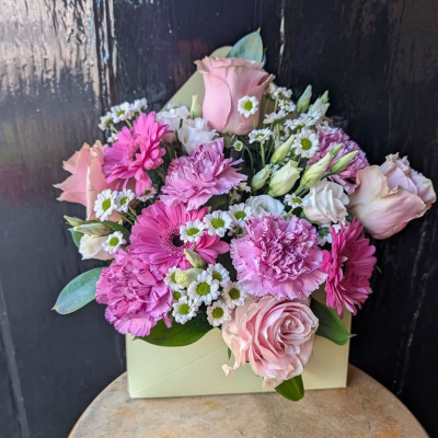 With Love, Envelope Bouquet - A charming letterbox-style envelope filled with pink gerbera, ruffled cerise carnations, soft pink roses and white lisianthus, scattered with dainty white daisies. A sweet way to send a heartfelt message.