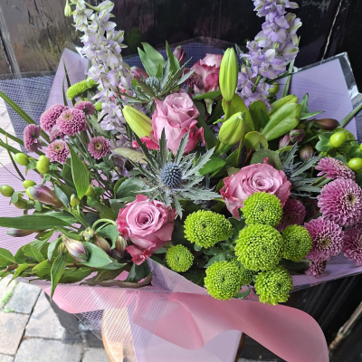 Highland Romance Bouquet - A romantic hand-tie of mauve roses, lilac delphinium, blue thistle, lime-green chrysanthemums and dusky pink blooms, wrapped in soft pink. Textured, contemporary and full of character.